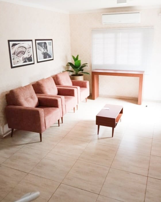 Sala de espera da Spin Estética, com poltronas rosadas e uma planta